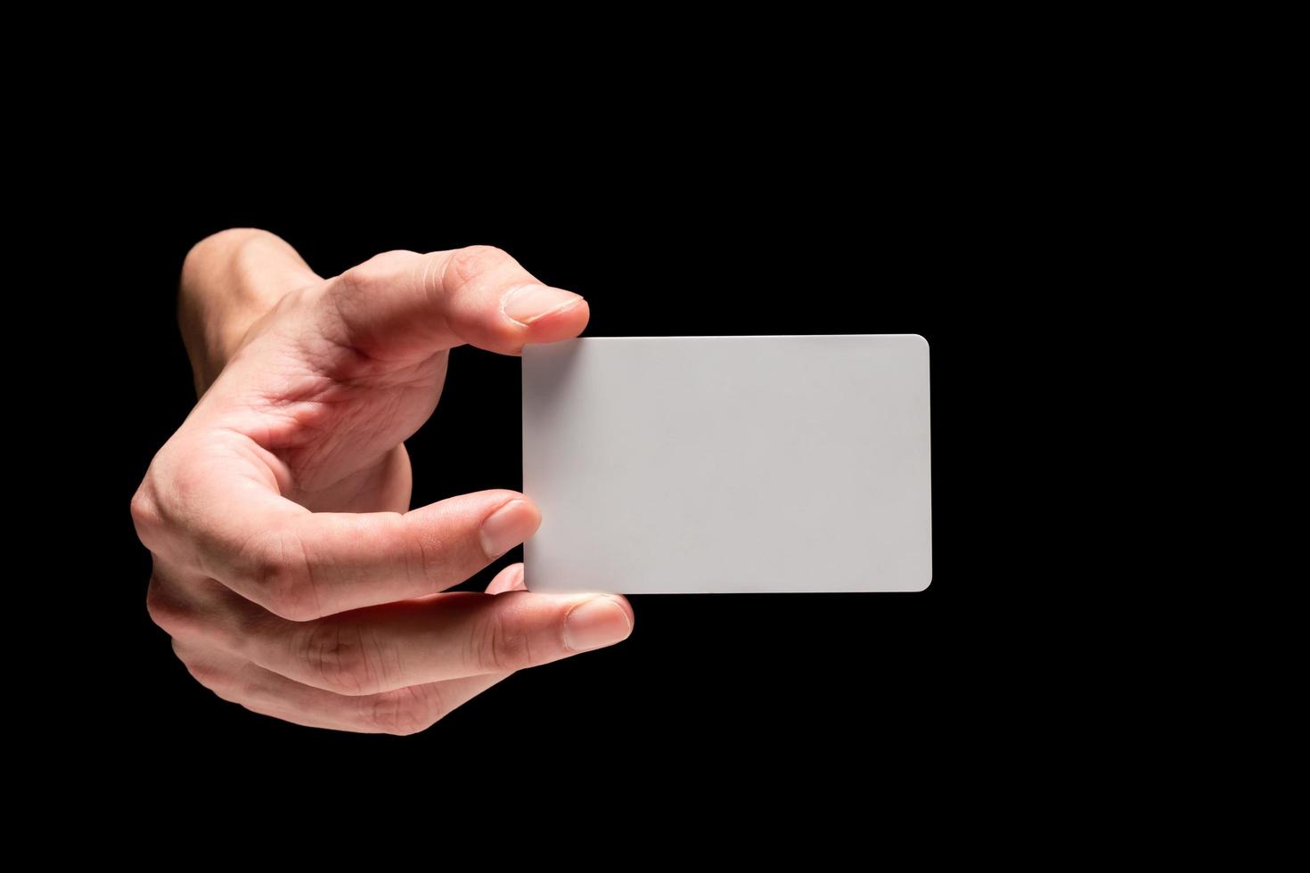 Male hand holding card on a black background. photo