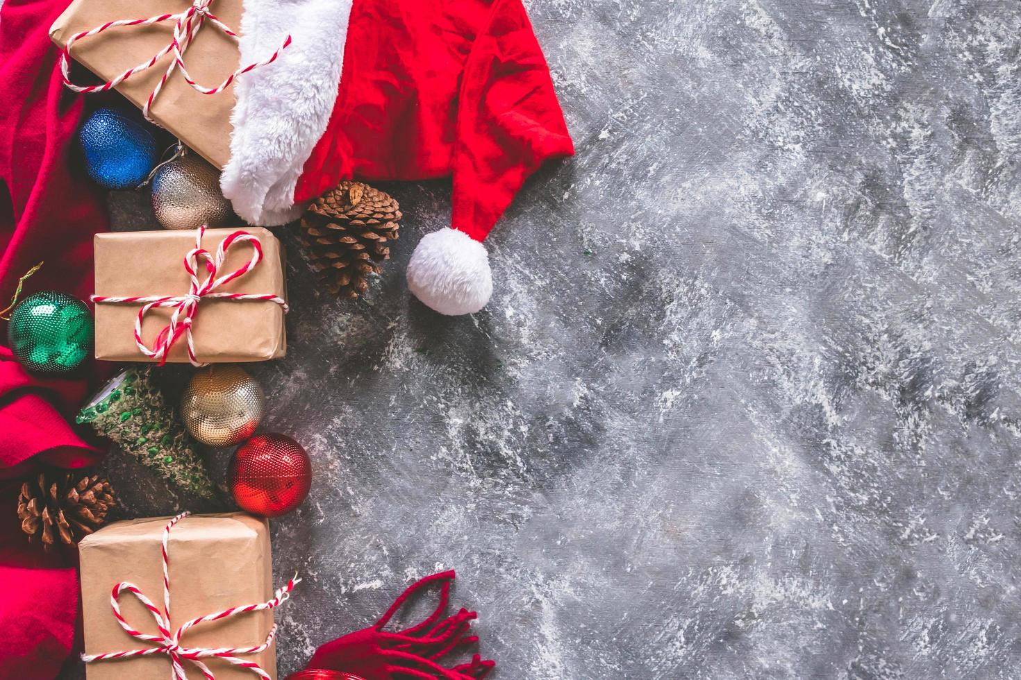 Top view of gift packages wrapped in brown paper with christmas decoration on gray grunge background. Free space for text photo