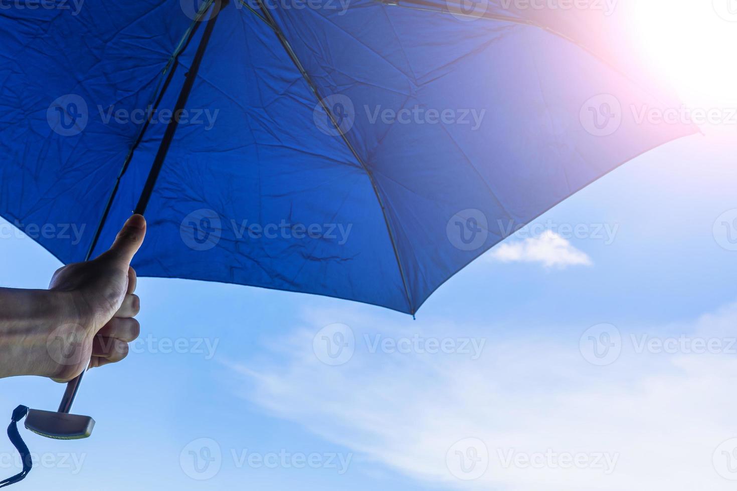 Hand holding umbrella with blue sky and sunlight background photo