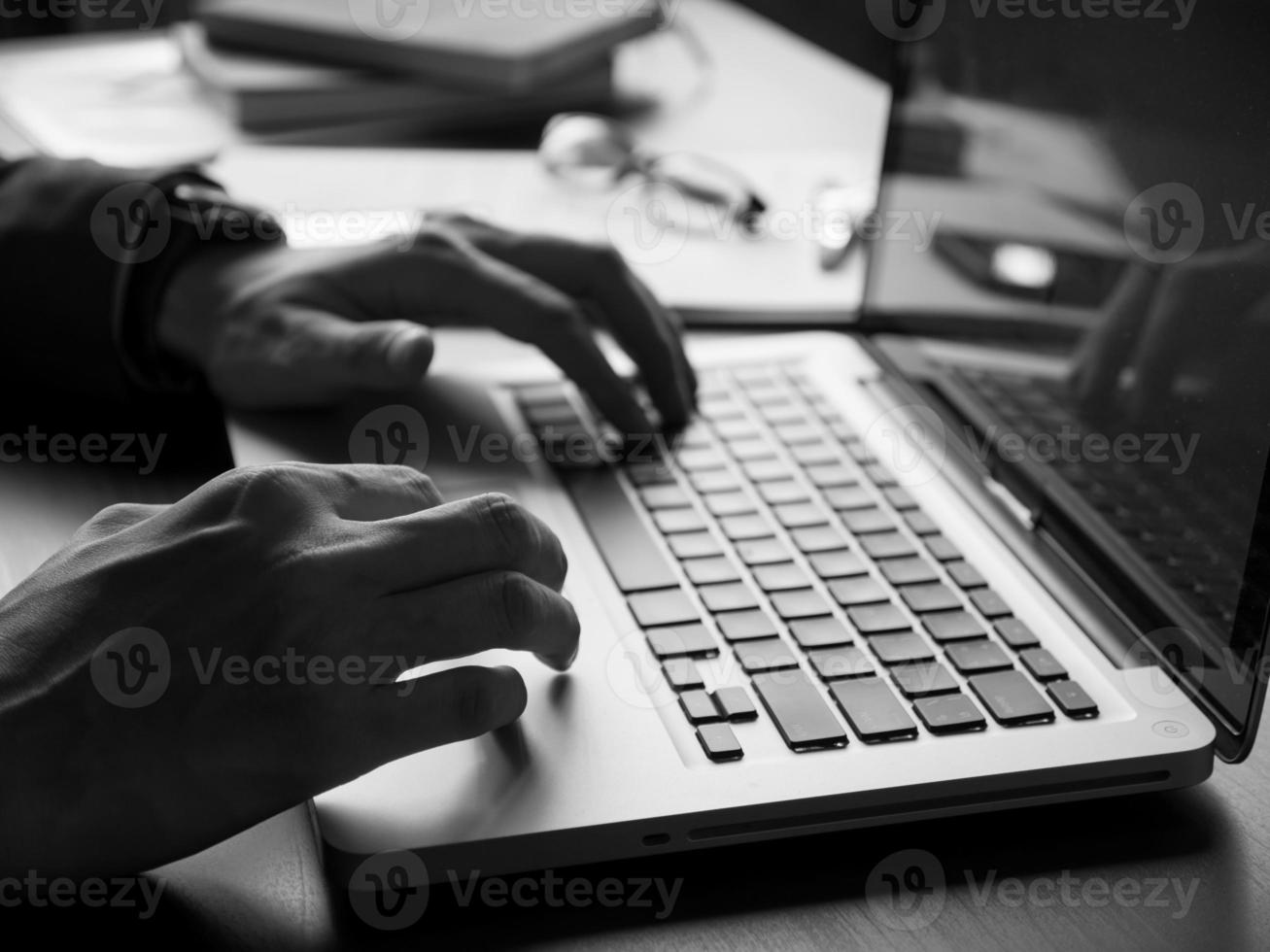 primer plano de un hombre de negocios que usa una computadora portátil en el escritorio de la oficina. tono blanco y negro foto