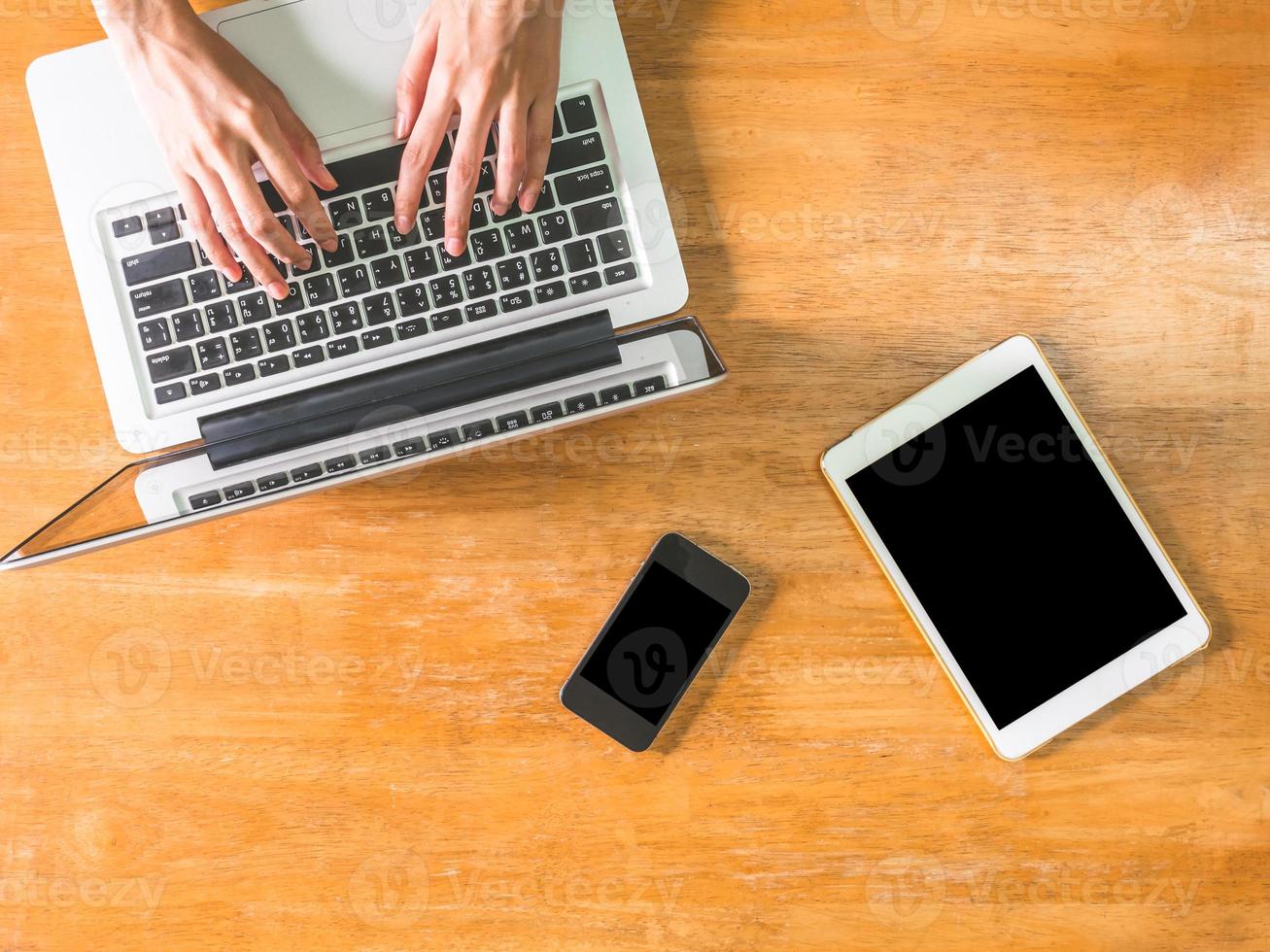 Top view of Male hands using Laptop, tablet with smart phone on wooden table. photo