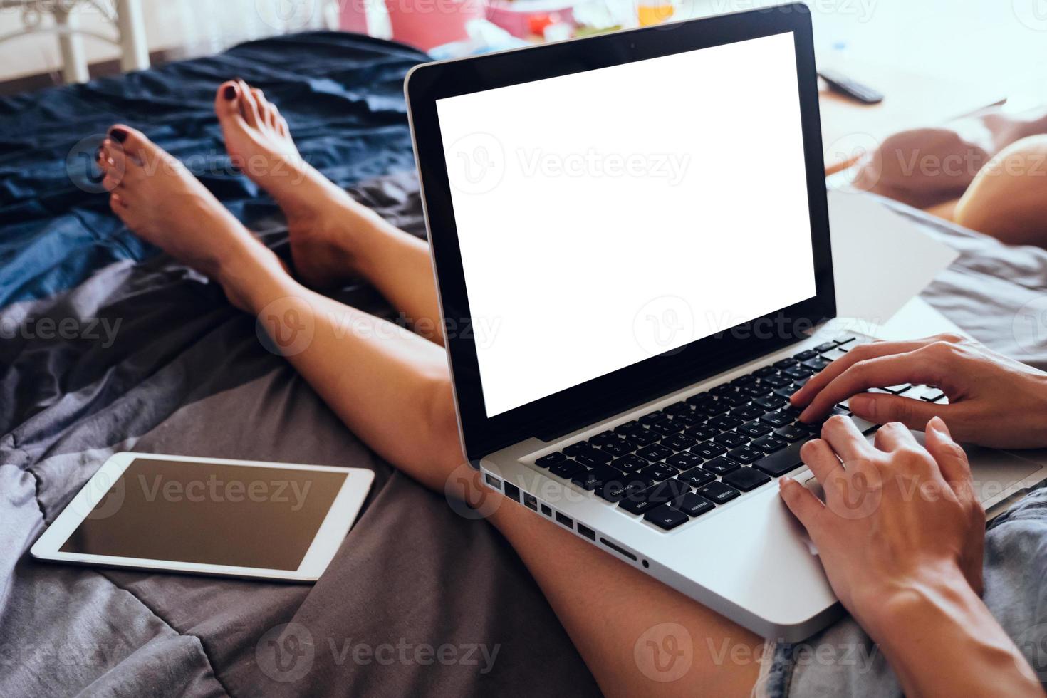Close up of young woman using laptop while sitting on her bed,  Films grain filter. photo