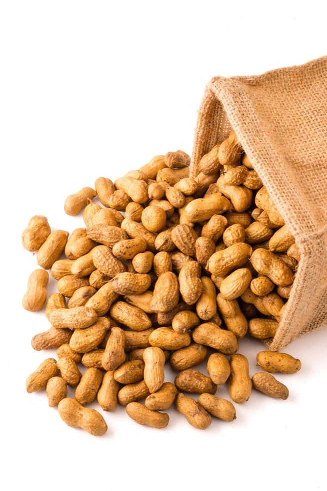 Peanuts in burlap bag on white background. photo