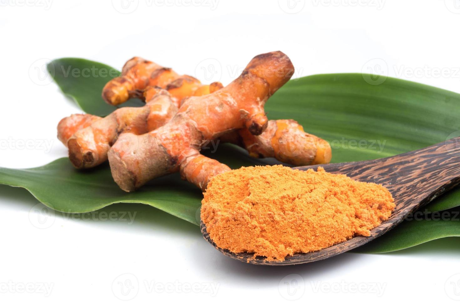 Turmeric roots with turmeric powder on green leaf over white background. photo