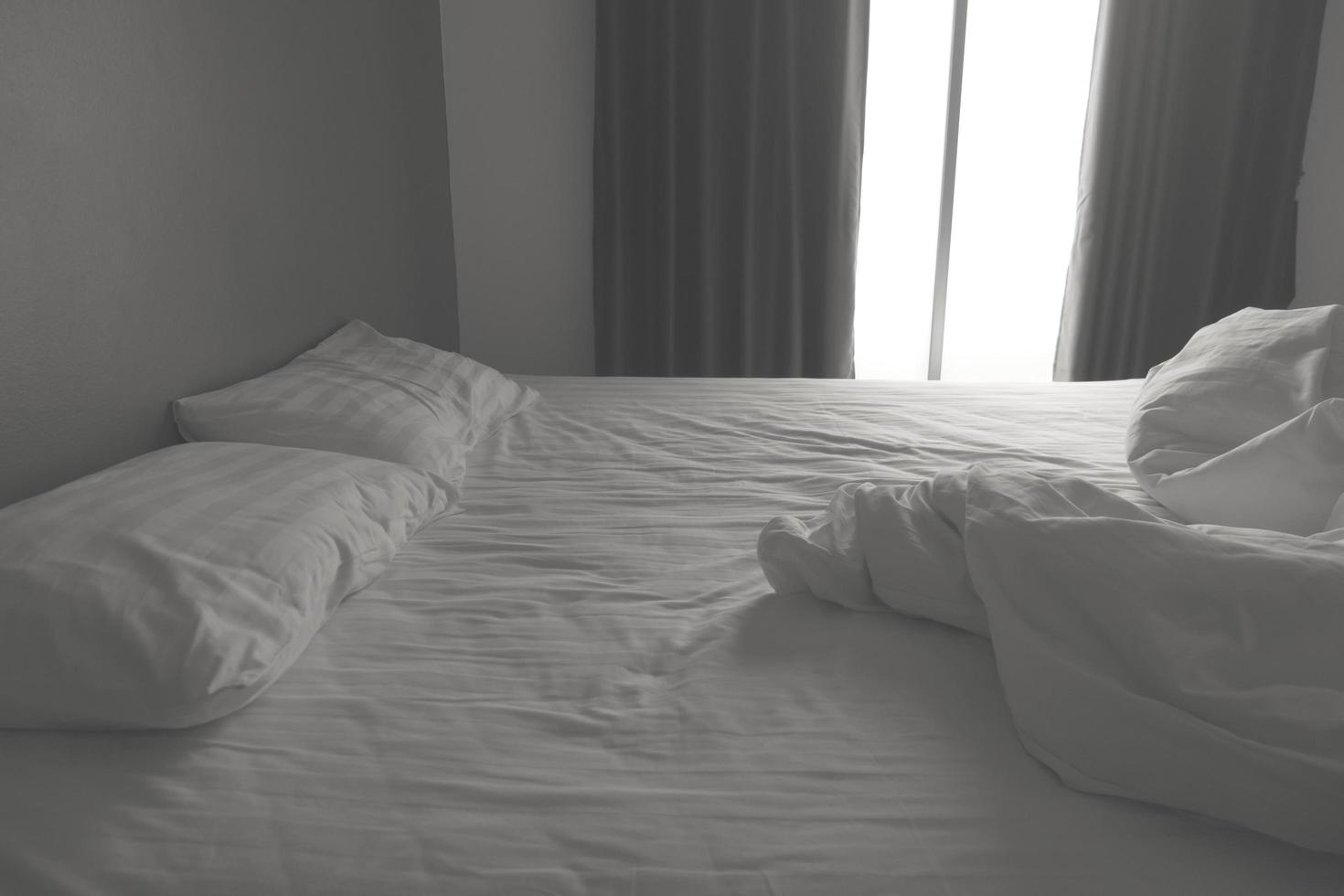 Messy white bedding sheets and pillows. black and white tone photo