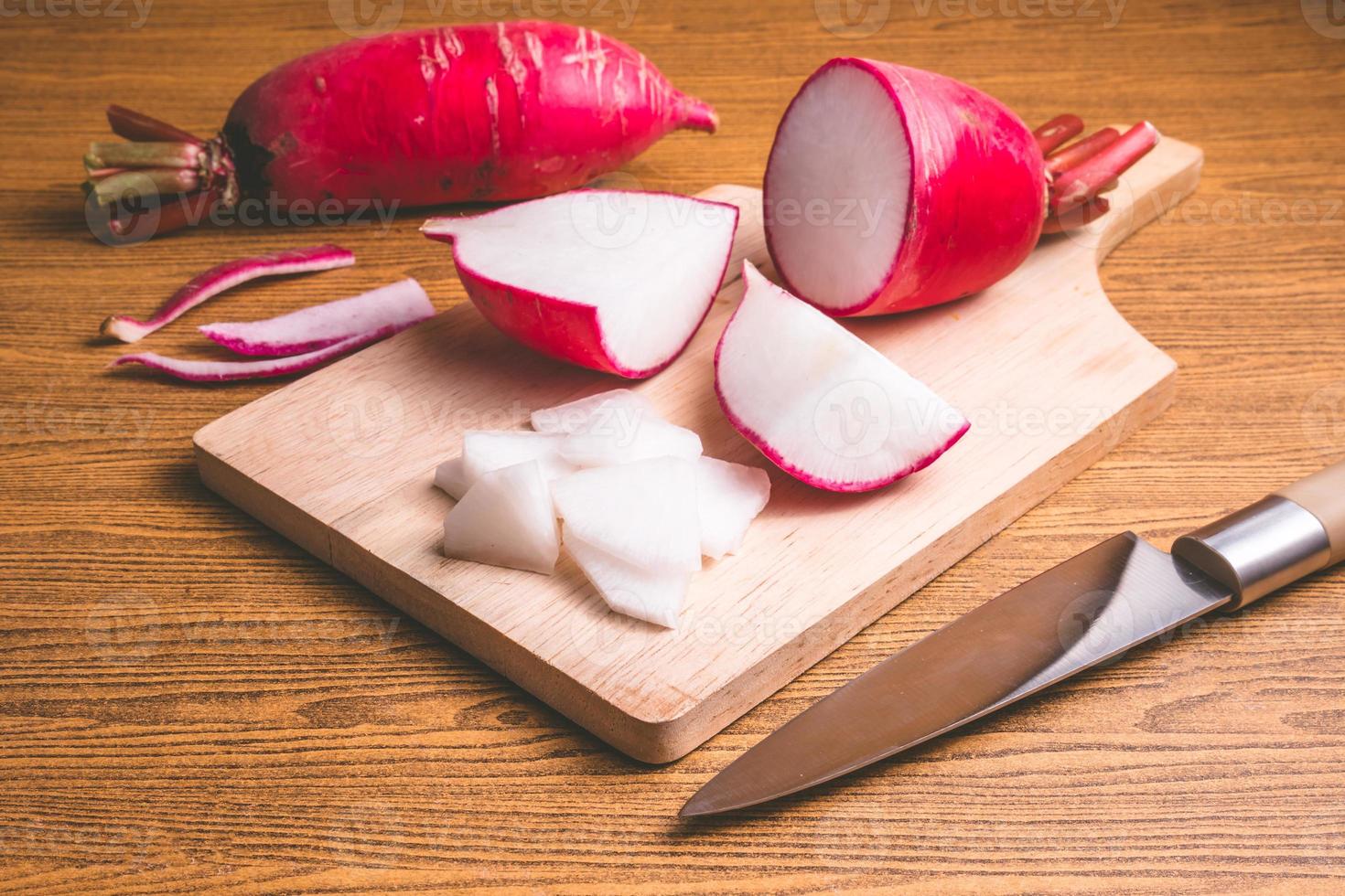 Fresh Pink Radishes on wooden cutting board over wooden table background. photo