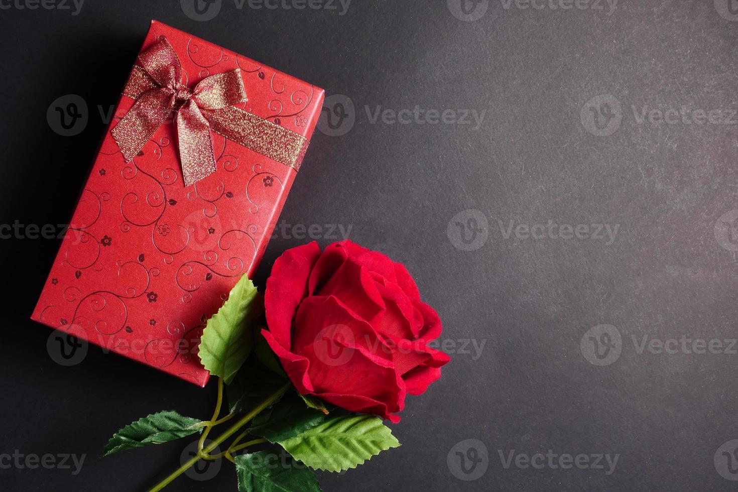 Red rose with red gift box on black background. Free space for text. Concept of Valentine Day. photo
