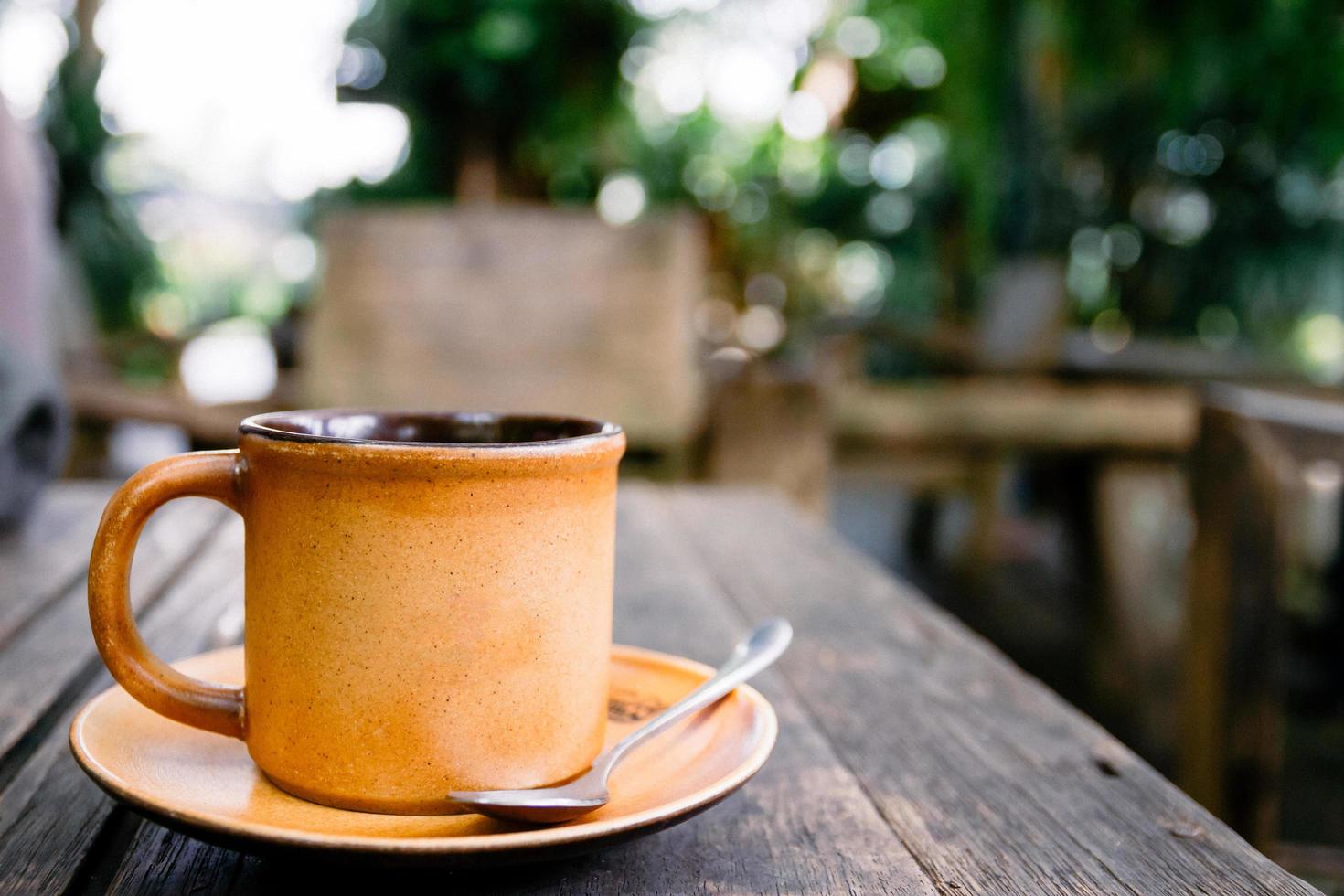 Cup of coffee on the wooden table in cafe. Films grain filter. photo