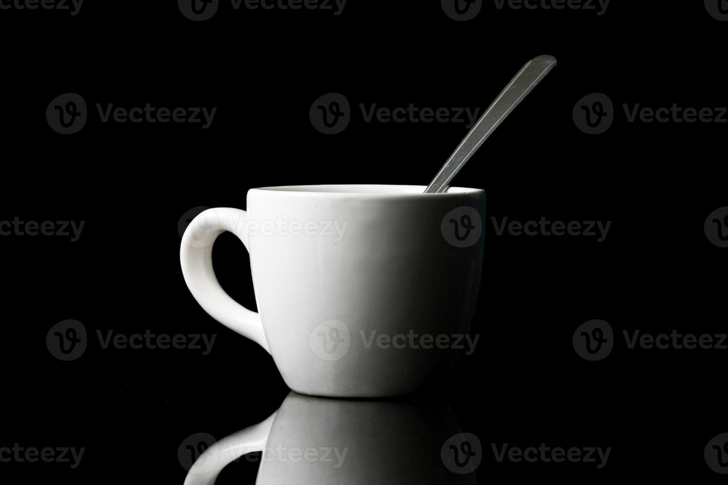 White cup with spoon on black background. photo