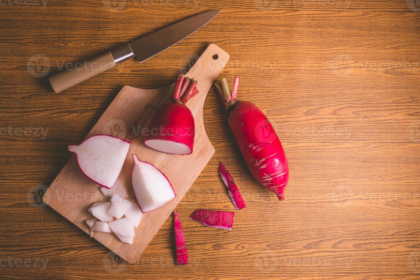 Fresh Pink Radishes on wooden cutting board over wooden table background. photo