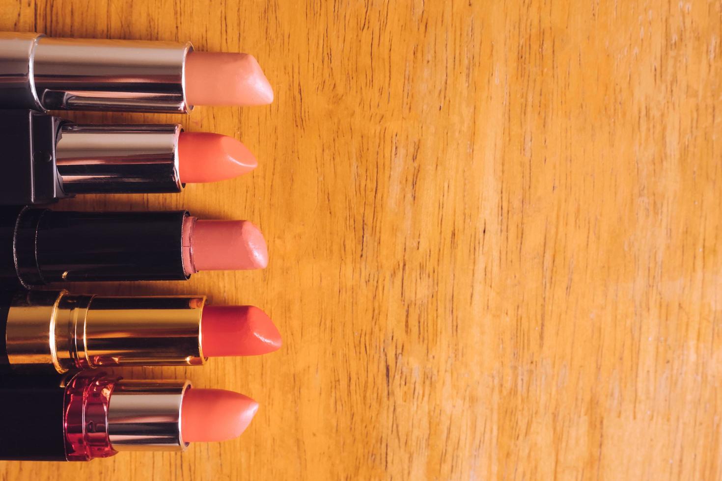 vista superior de barras de labios de colores en la mesa de madera. concepto de maquillaje y belleza foto