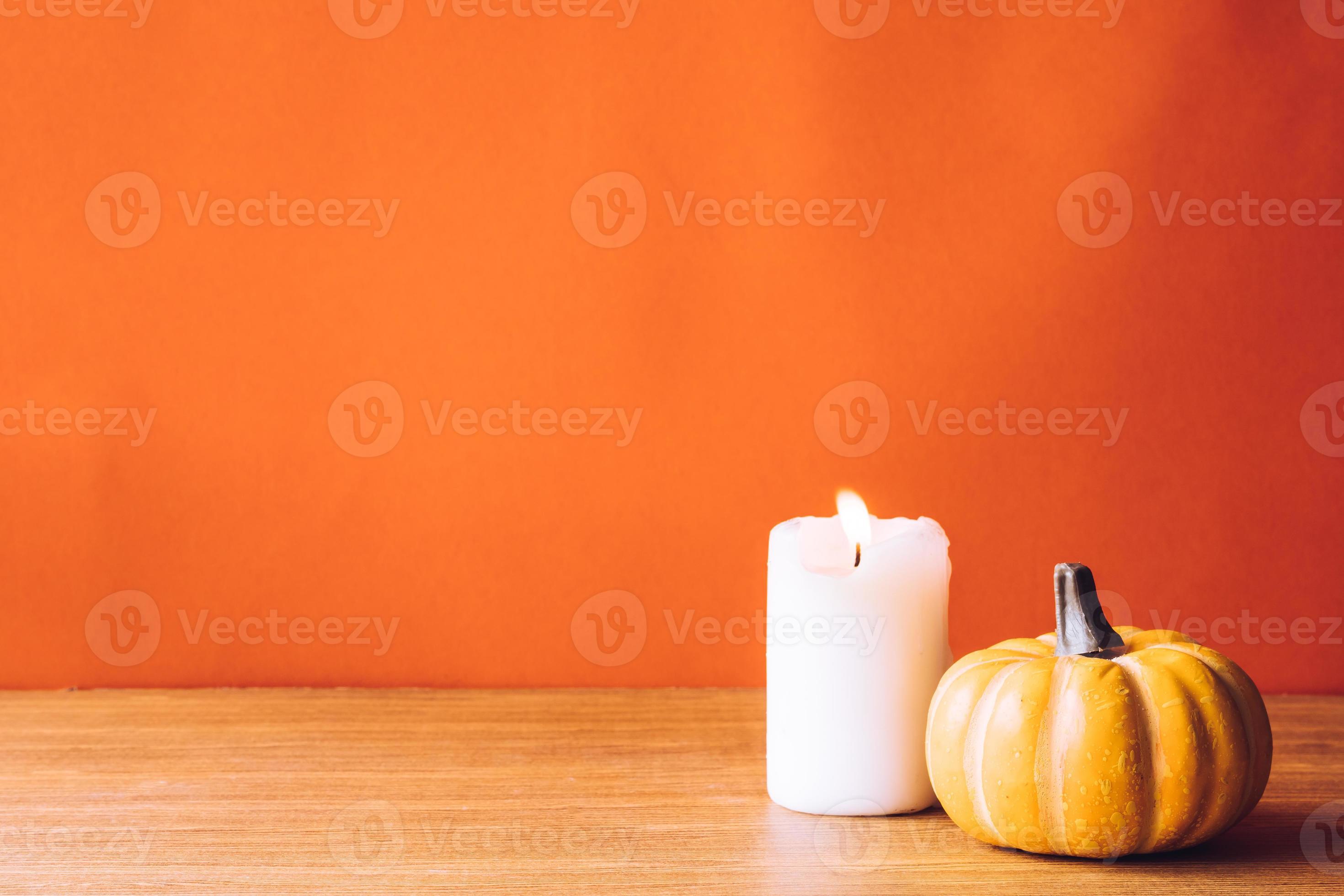 Pumpkin with candlelight on an orange color background. Free space for