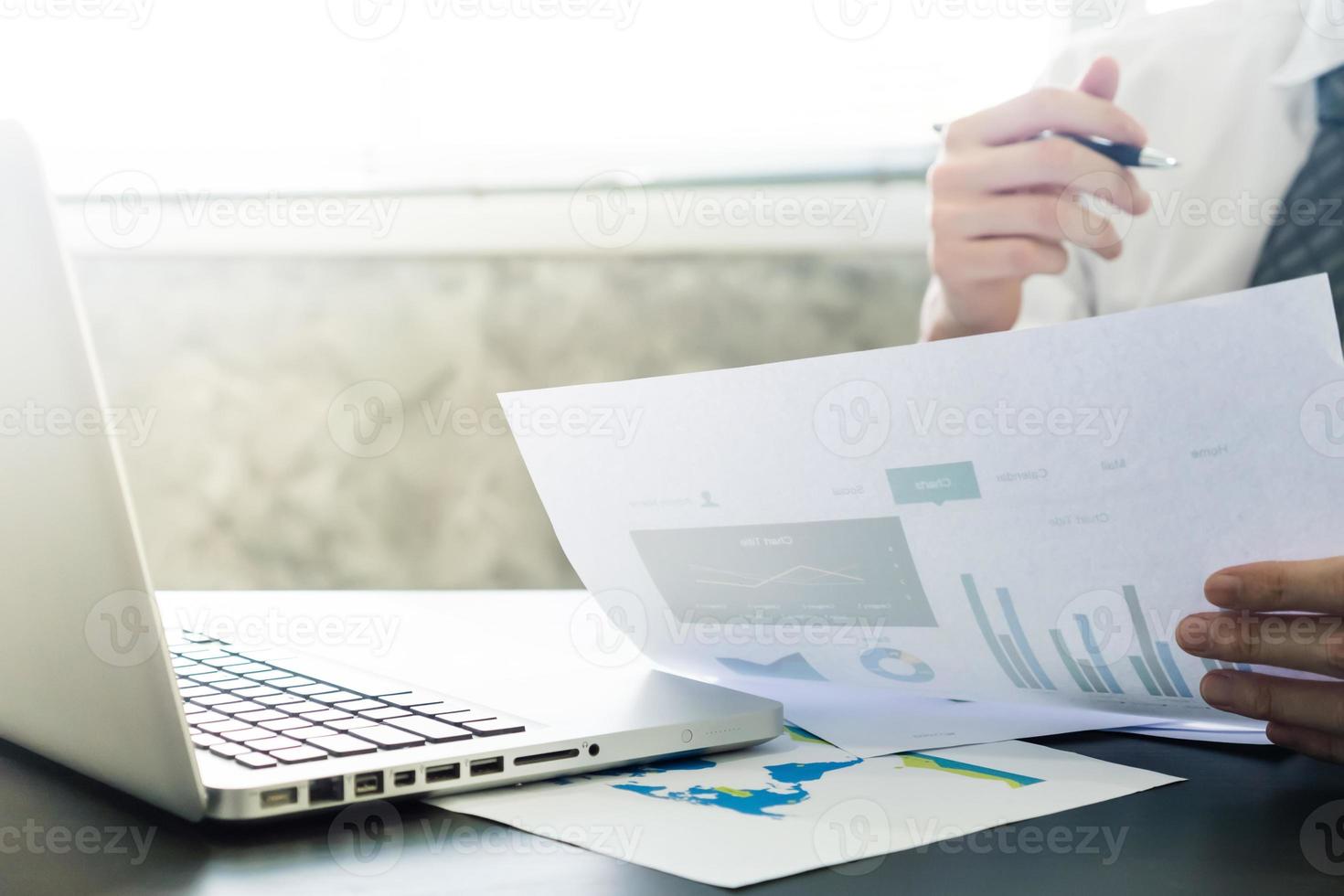 Close up of Businessman analyzing investment charts and using laptop on the desk. photo