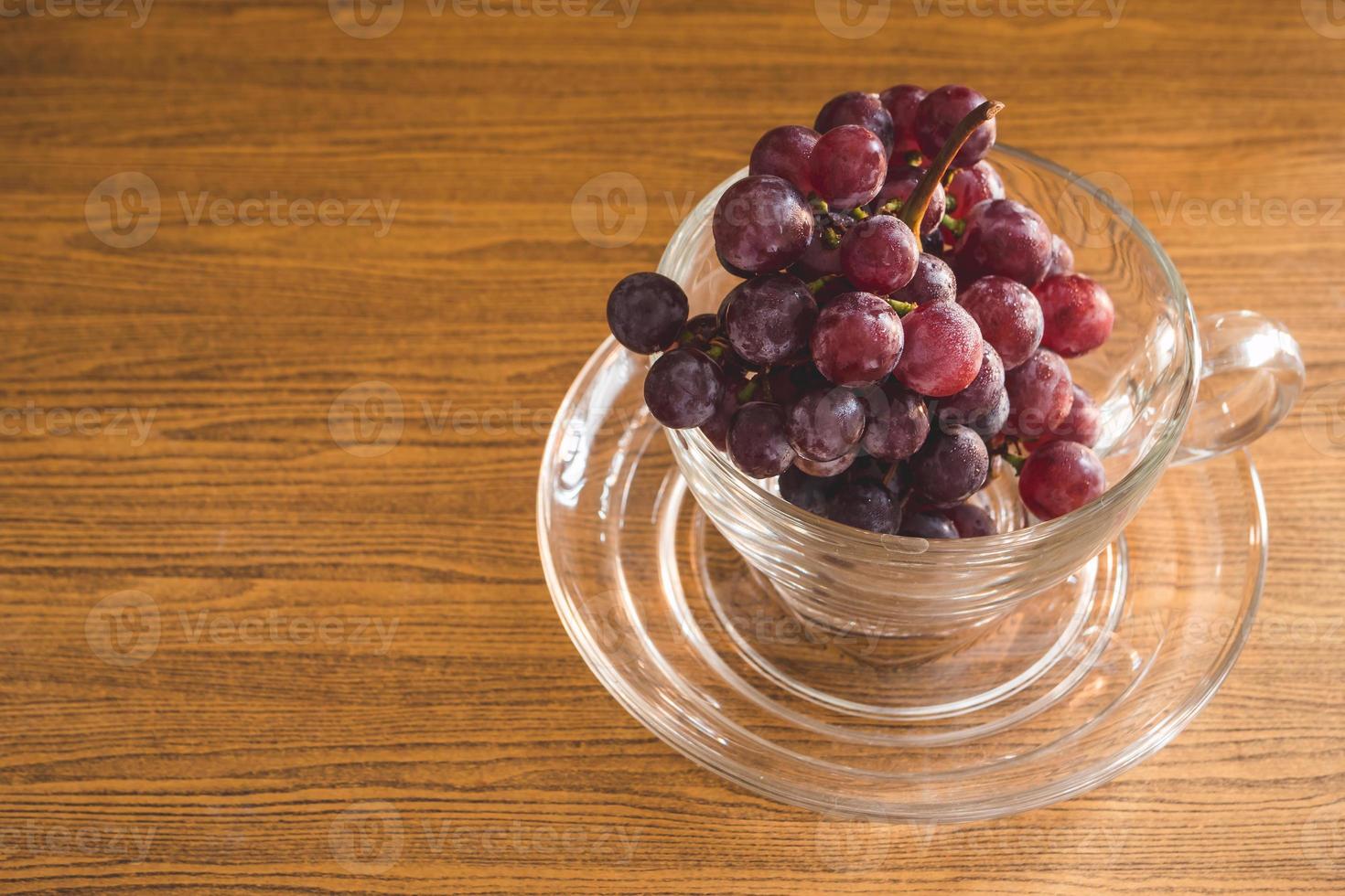 uvas rojas en vidrio sobre la mesa de madera. espacio libre para texto foto