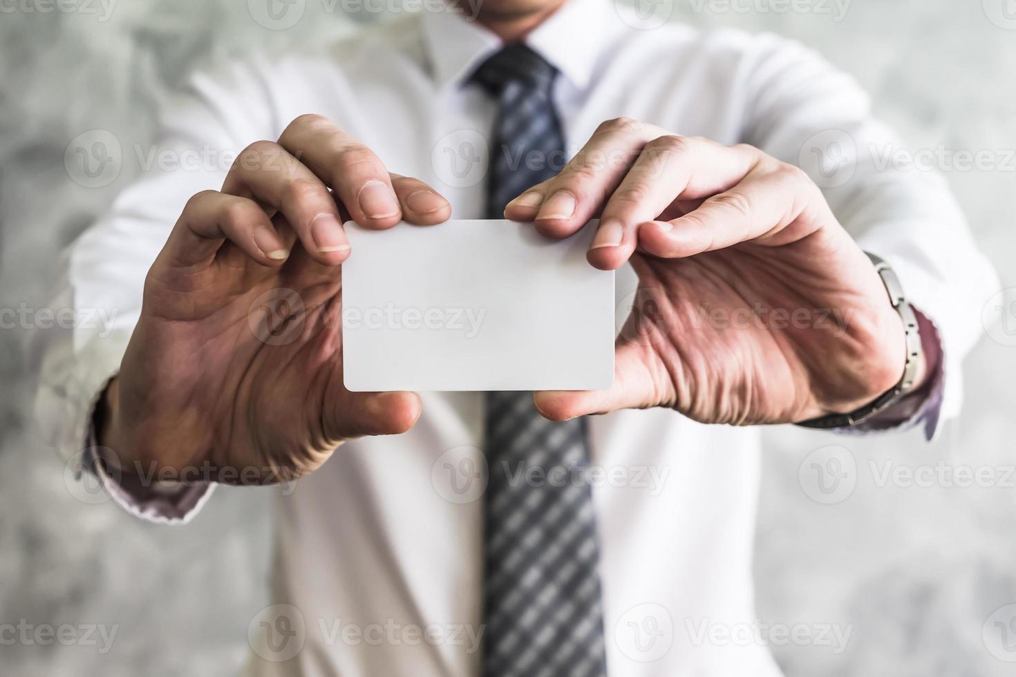 primer plano de un hombre de negocios que sostiene una tarjeta blanca en blanco sobre un fondo grunge. foto