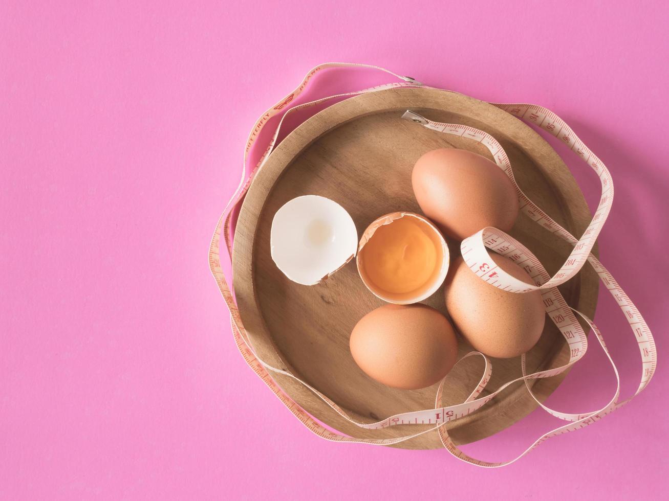 Eggs with tape measure on pink background. photo