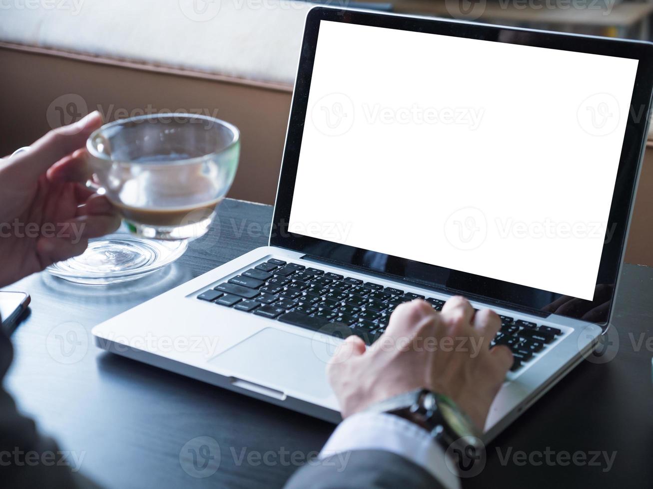 Close up of businessman using a laptop with white screen on the desk. photo