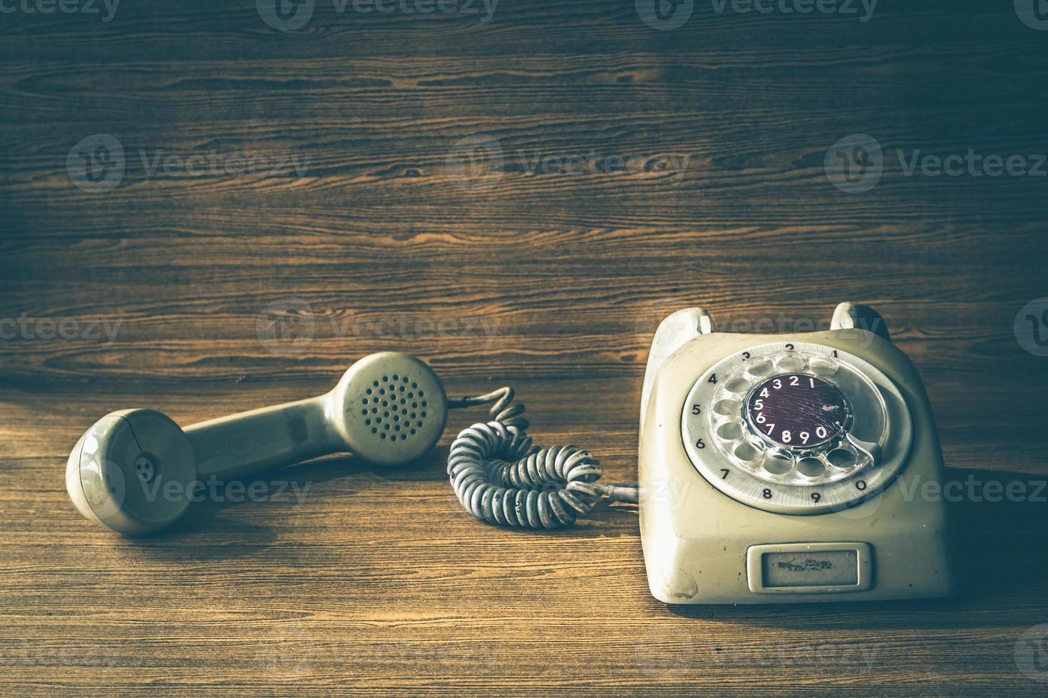 Old telephone on wooden table background. Vintage tone photo