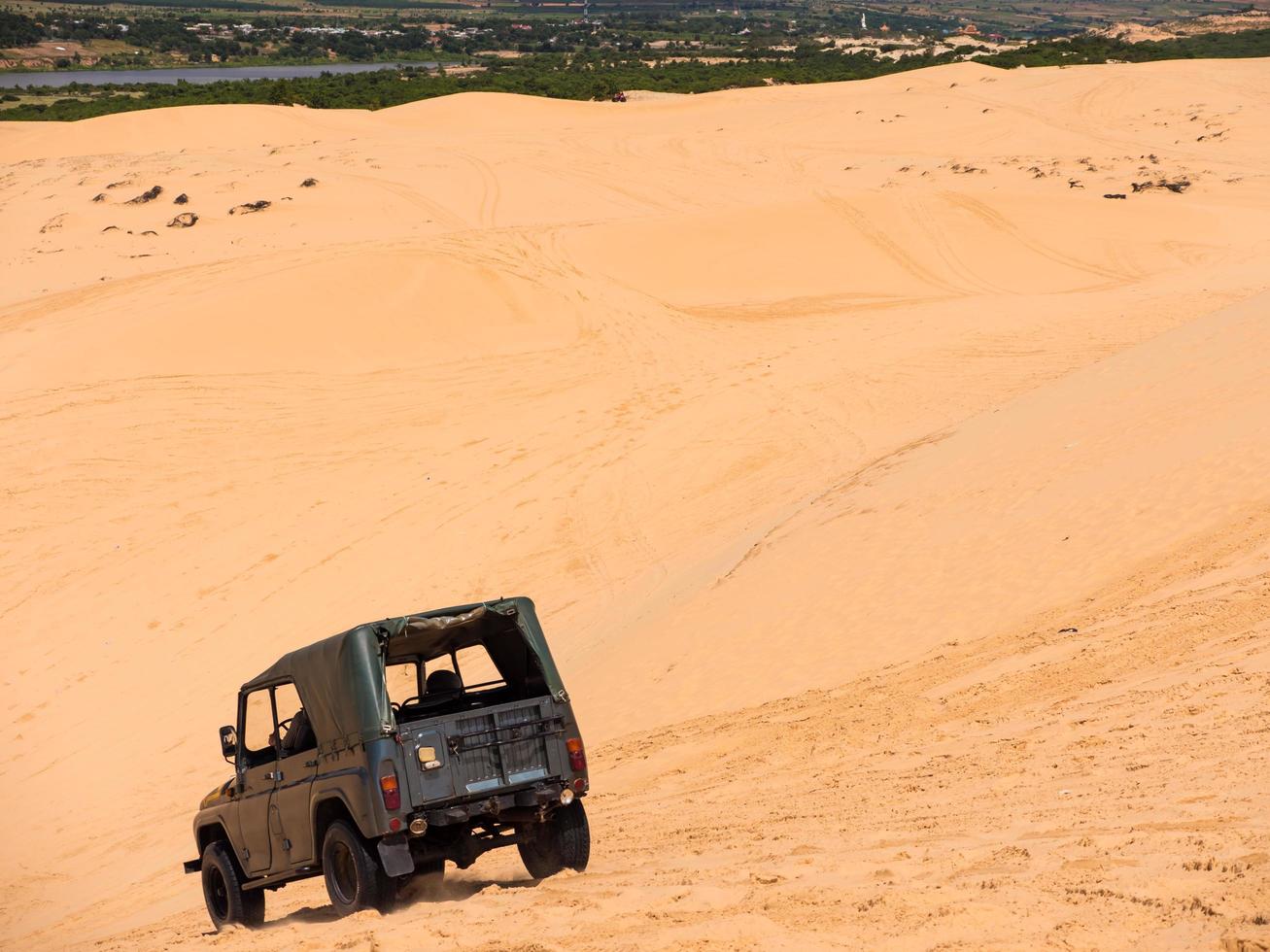 Jeep car on Yellow sand dunes in Mui Ne is a popular tourist destination of Vietnam photo