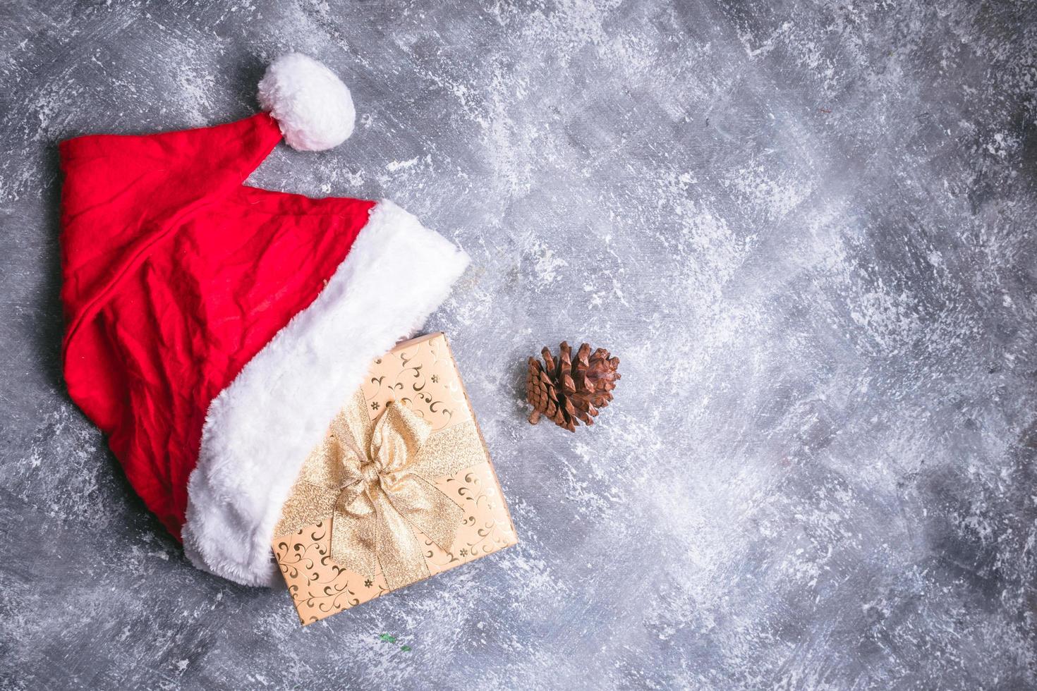 Top view of santa hat with gift box on gray grunge background. Free space for text photo