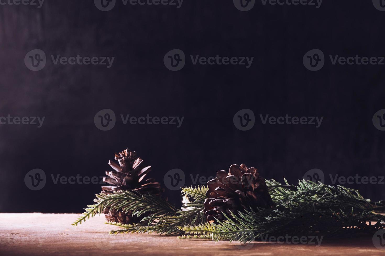 Pine cones with branches on the wooden table, black background, free space for text photo