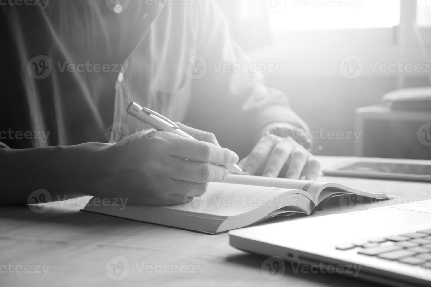 Close up of casual man writing note and using laptop on the desk, toned with sunlight photo