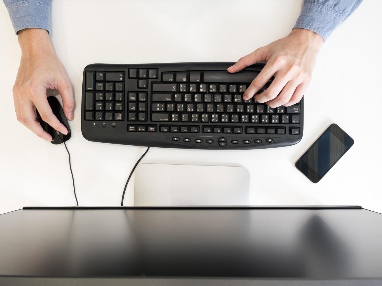 Top view of male hands working on computer on the desk. photo