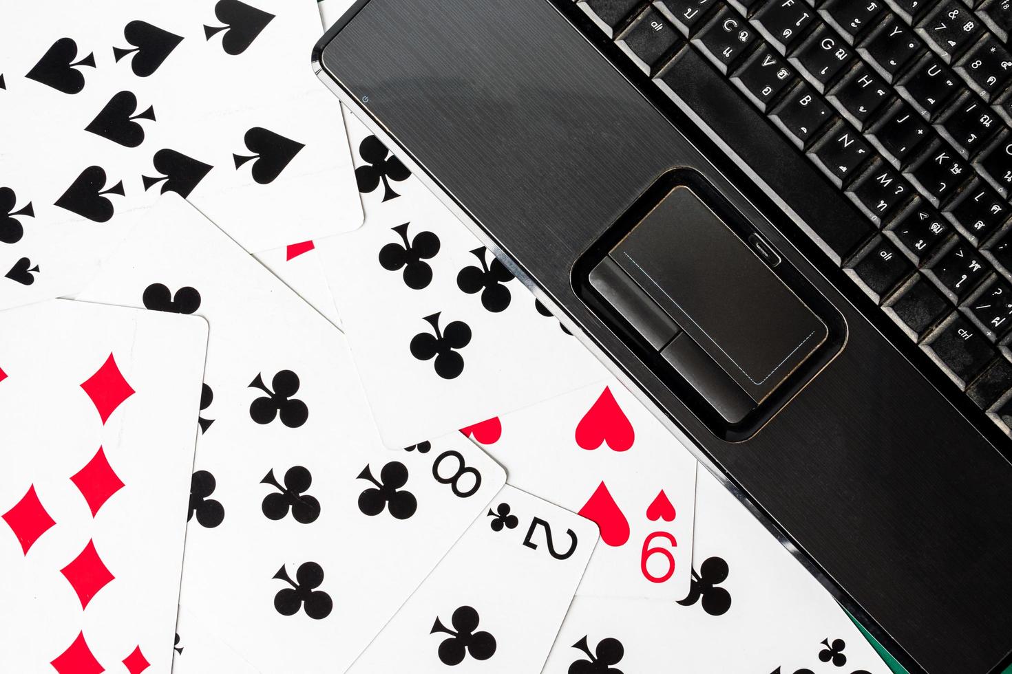 Close up of laptop keyboard on playing cards background. photo