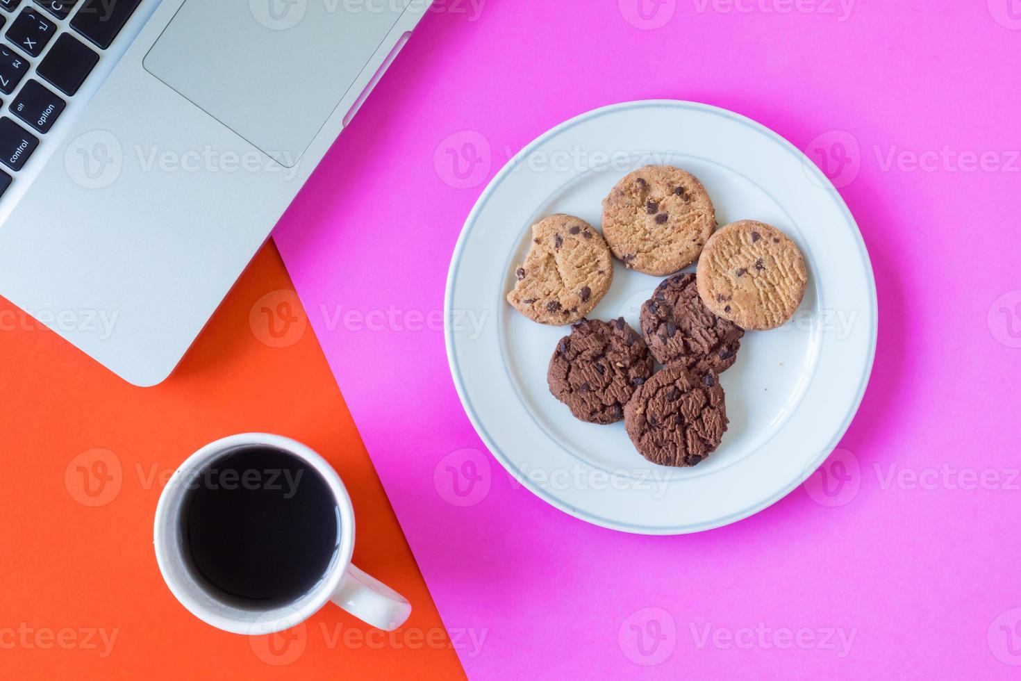 Cookies with coffee cup and laptop on colorful background. photo