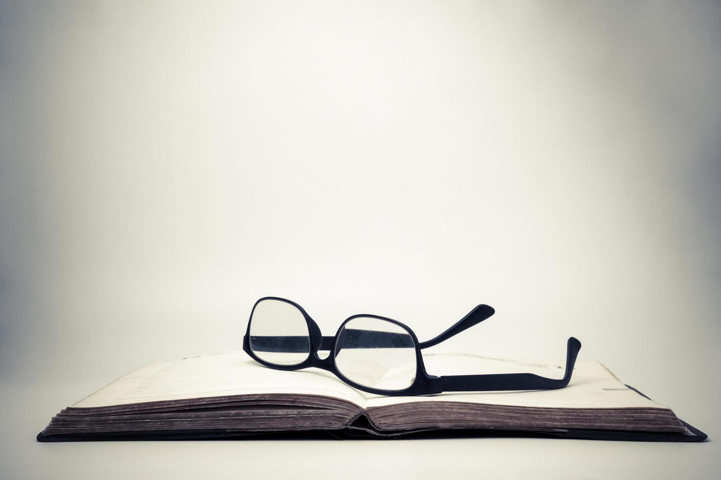 Eyeglasses on an open book with vintage background. photo