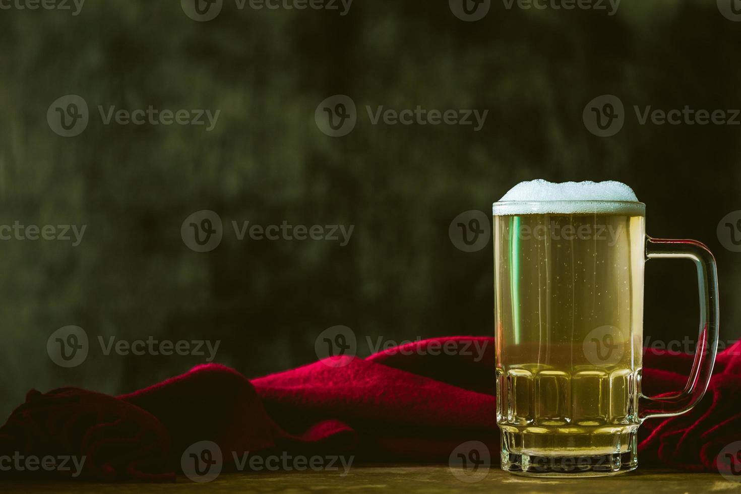 Mug of beer with red scarf on the wooden table. Free space for text photo