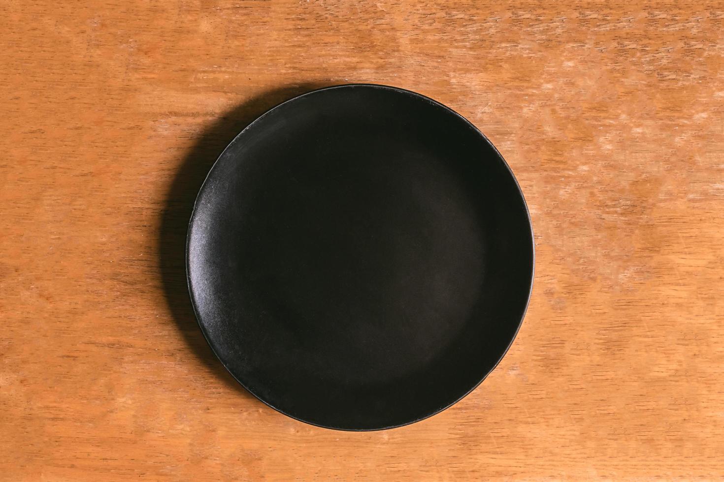 Top view of empty black plate on wooden table photo