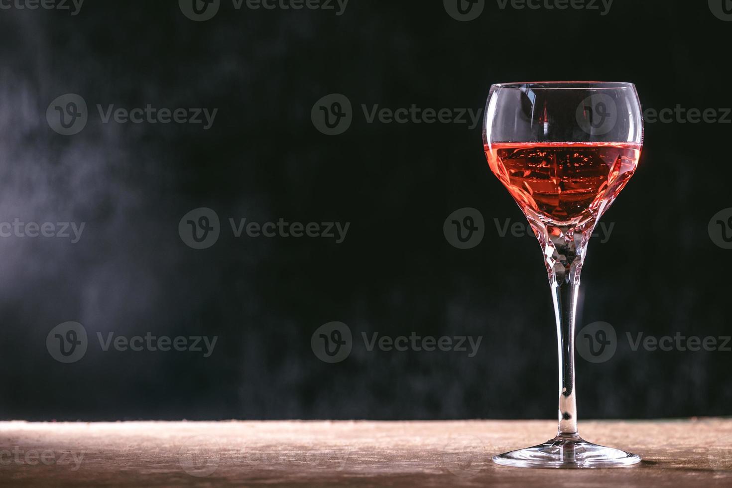 Glass of wine on the wooden table, black background. free space for text. photo