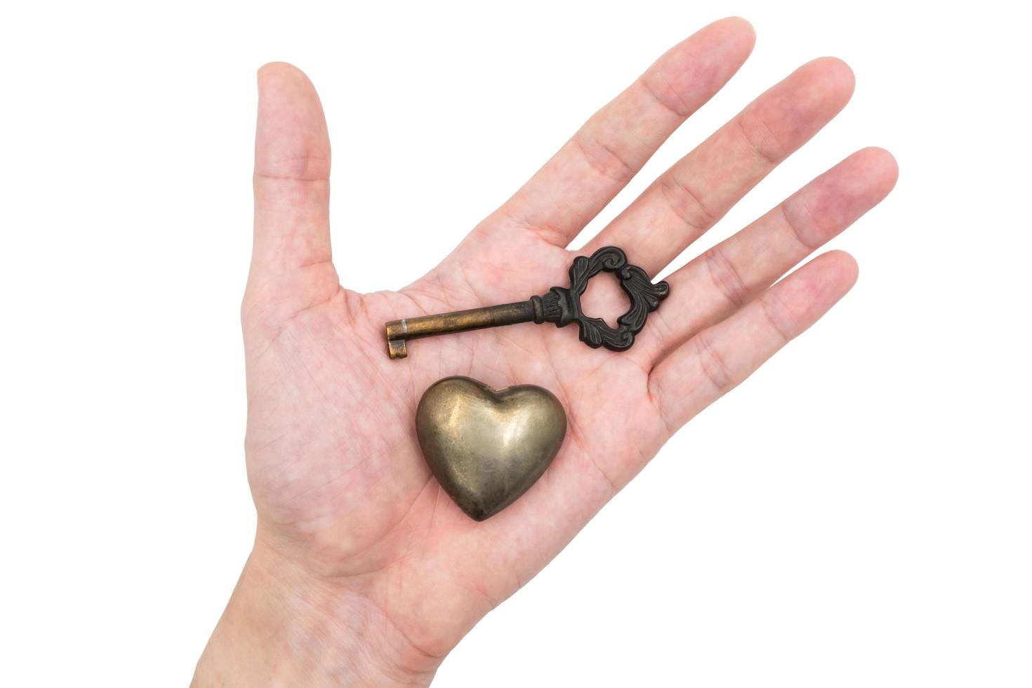 Male hand holding metal heart with key on white background, Metaphor love concept. photo