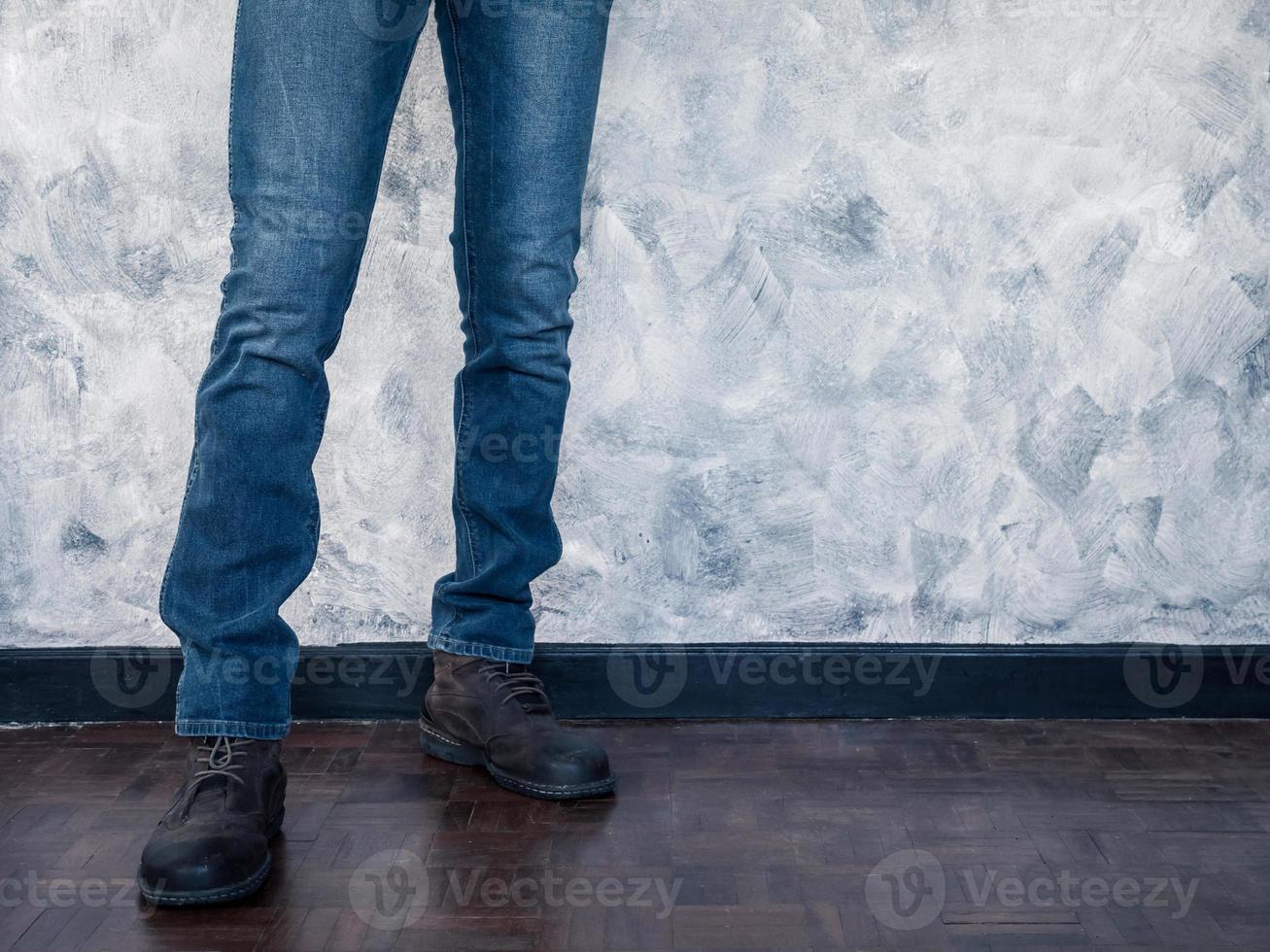Close up of Man's legs in jeans and boots on wooden floor. Free space for text photo
