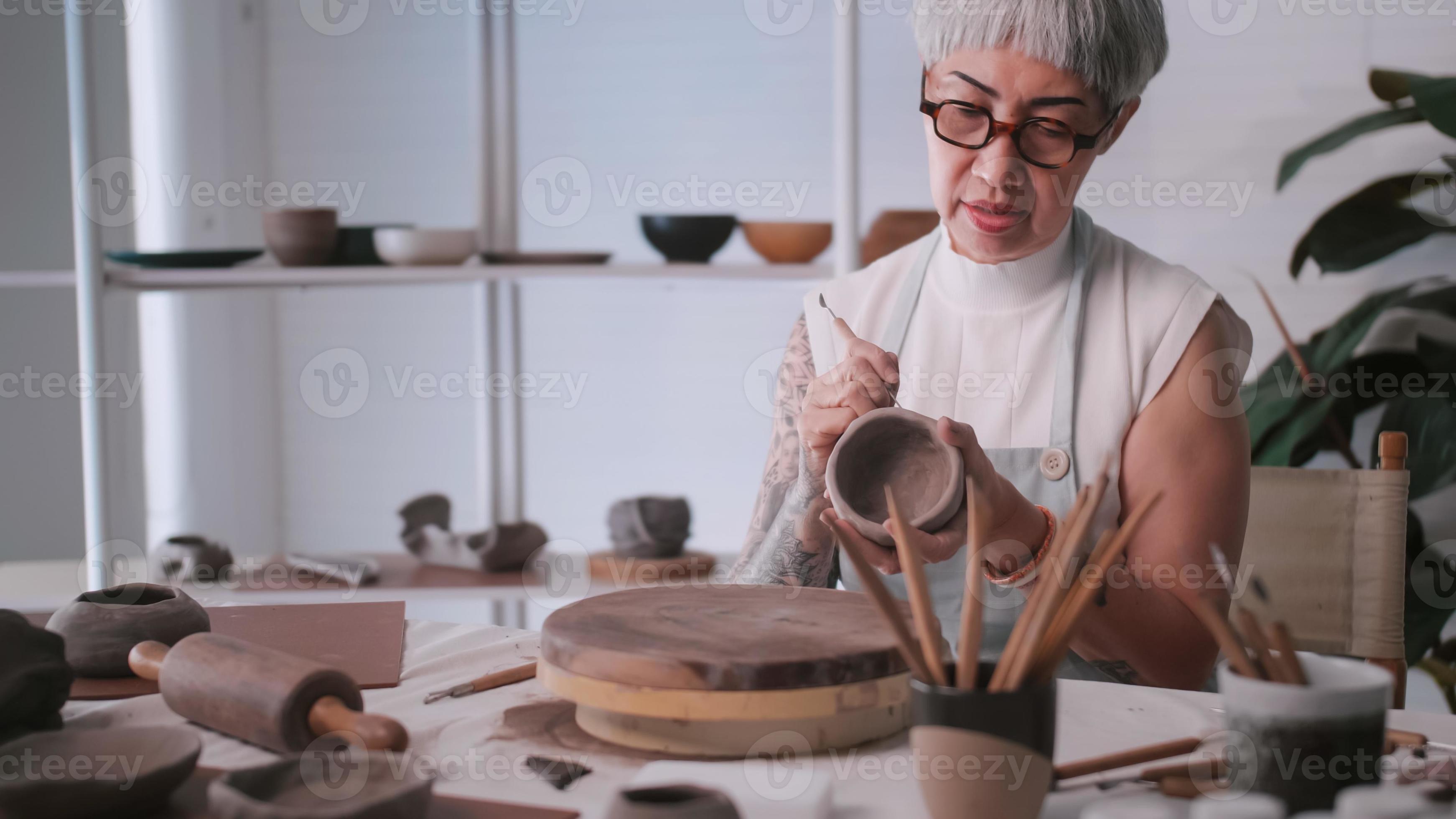 Asian elderly woman enjoying pottery work at home. A female ceramicist