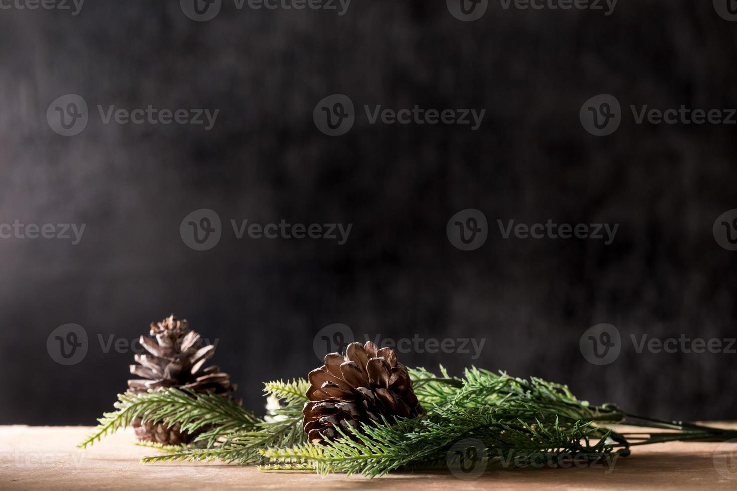 conos de pino con ramas en la mesa de madera, fondo negro, espacio libre para texto foto