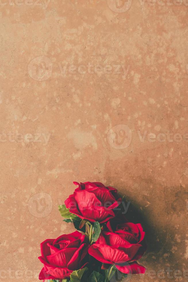 Bunch of Red roses on brown grunge board background. Free space for text photo
