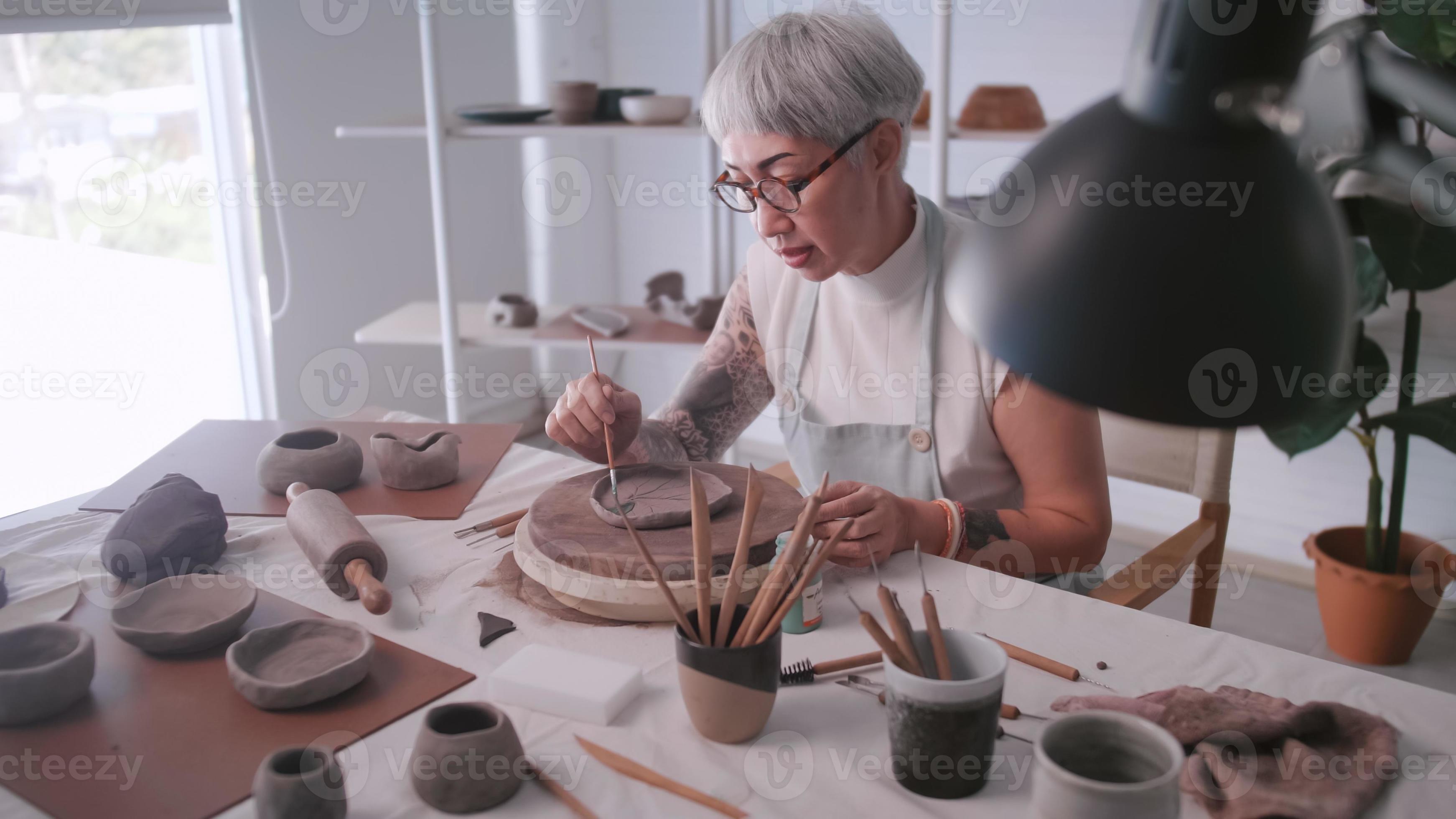 Asian elderly woman enjoying pottery work at home. A female ceramicist is making new pottery in