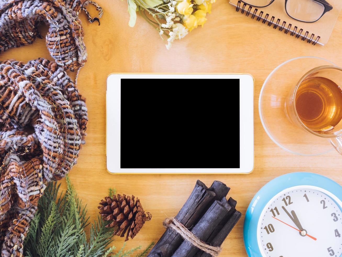 Top view of tablet with tea cup,clock, scarf and christmas decoration on wooden table. photo