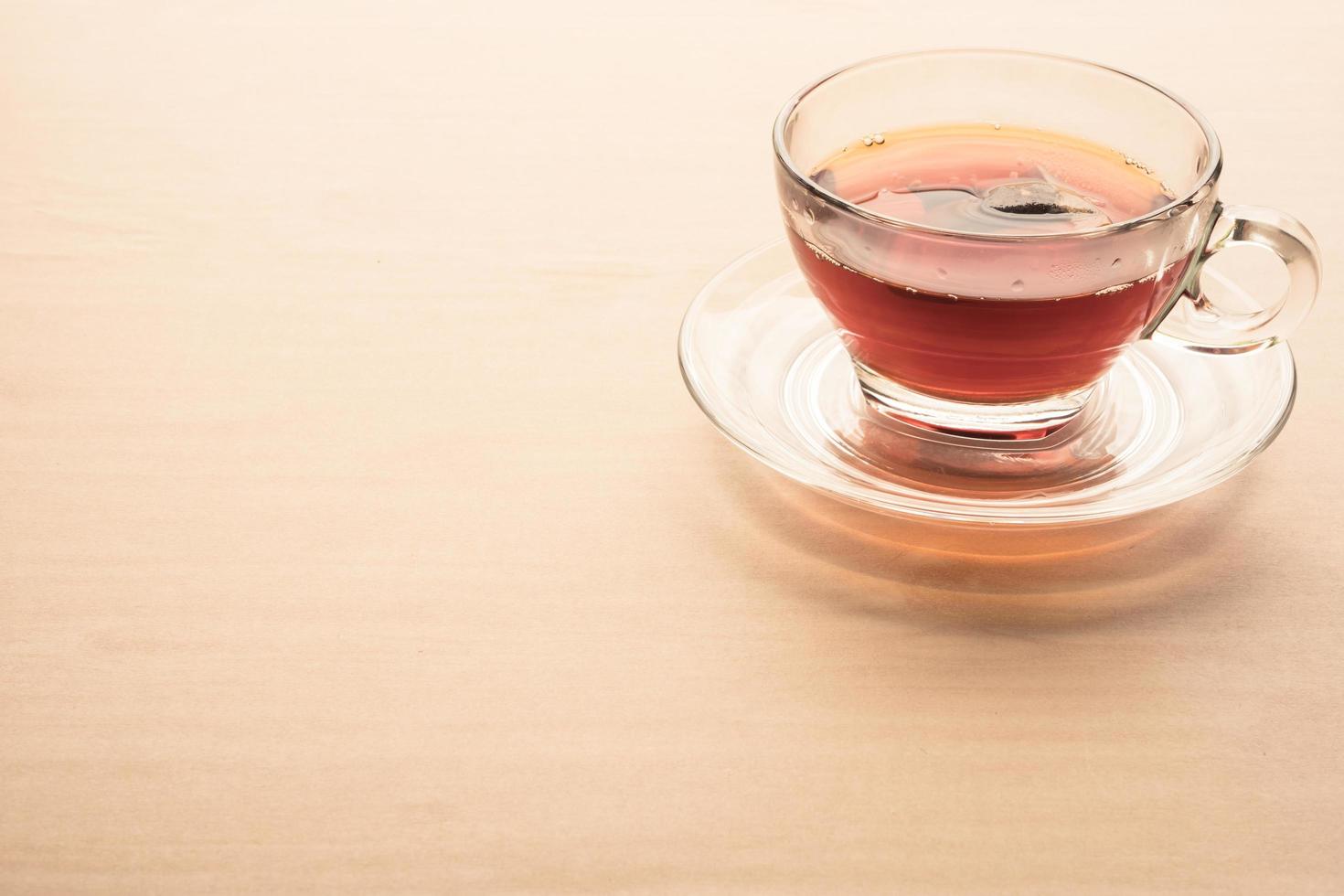 A cup of tea on the wooden table, tea bag in glass. photo
