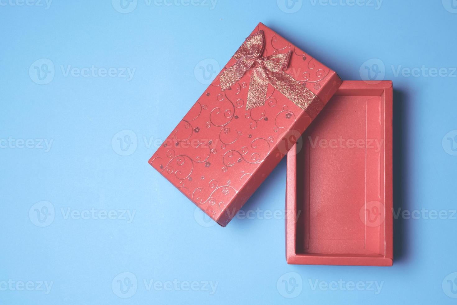 Top view of open red gift box on blue background. Free space for text photo