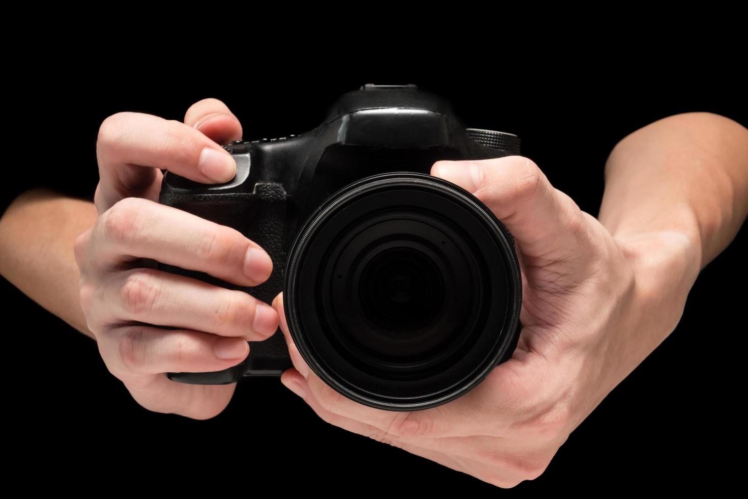 mano masculina sosteniendo una cámara digital sobre un fondo negro. foto