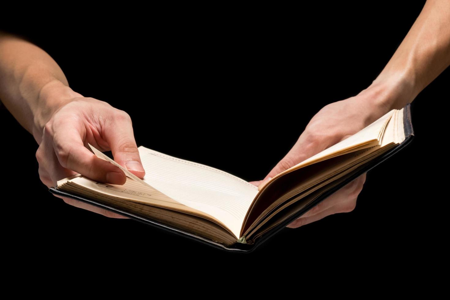 Male hands holding a blank notebook on a black background. photo