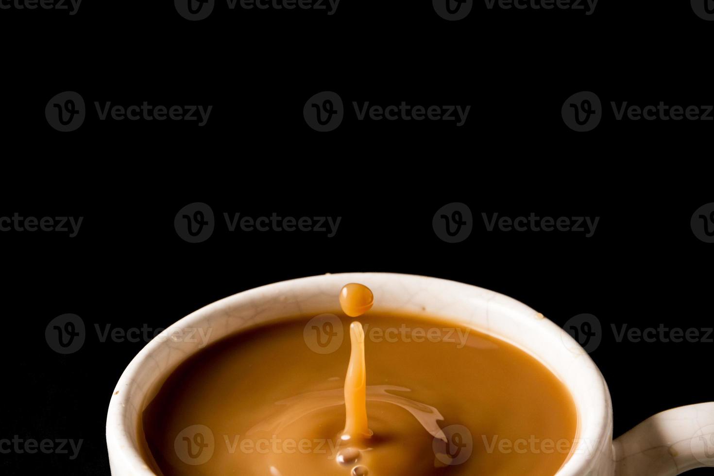 A cup of coffee with a drop on black background. photo