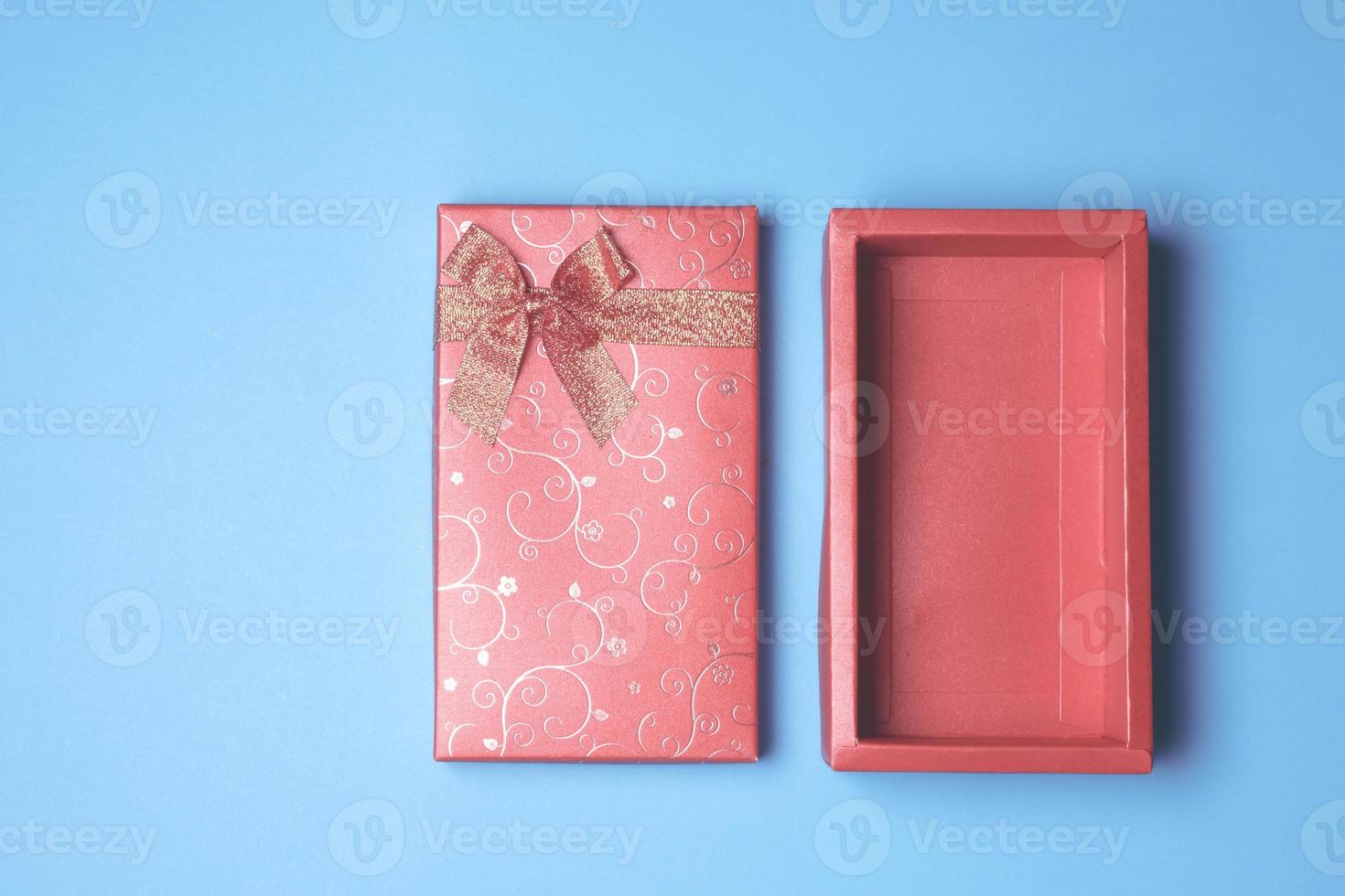 Top view of open red gift box on blue background. Free space for text photo