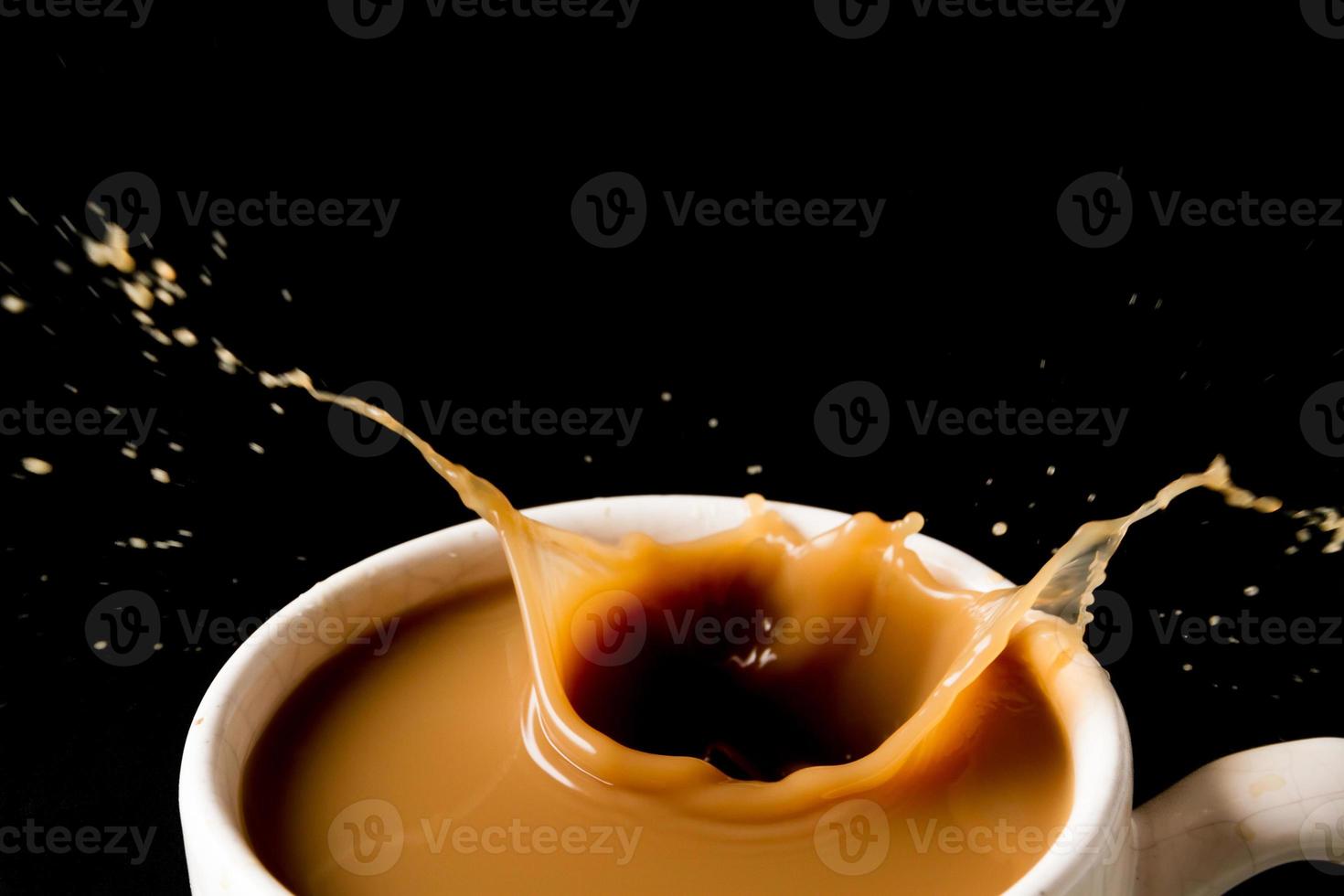 Cup of splashing coffee on black background photo