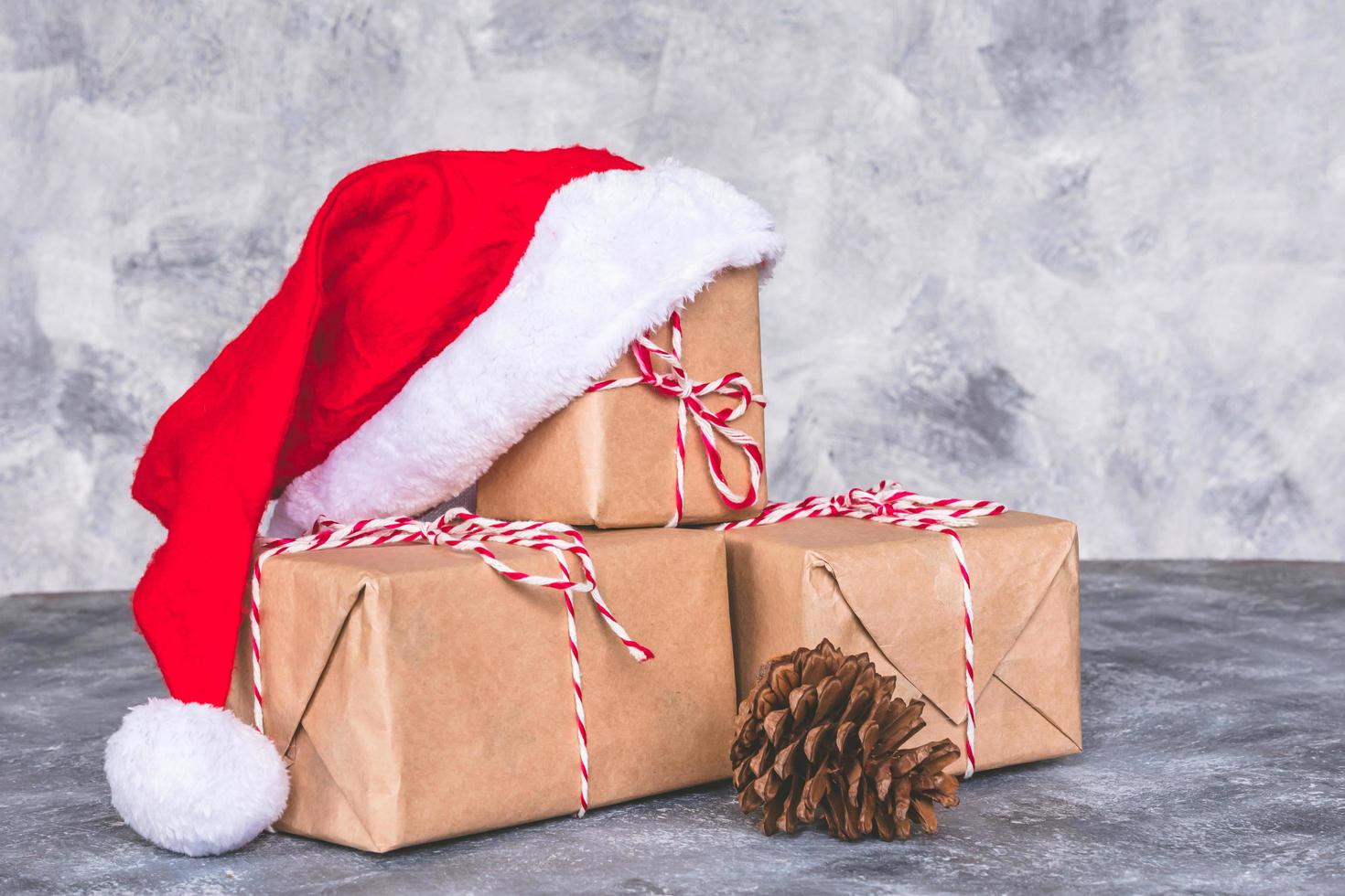 Top view of santa hat with gift box on gray grunge background. Free space for text photo