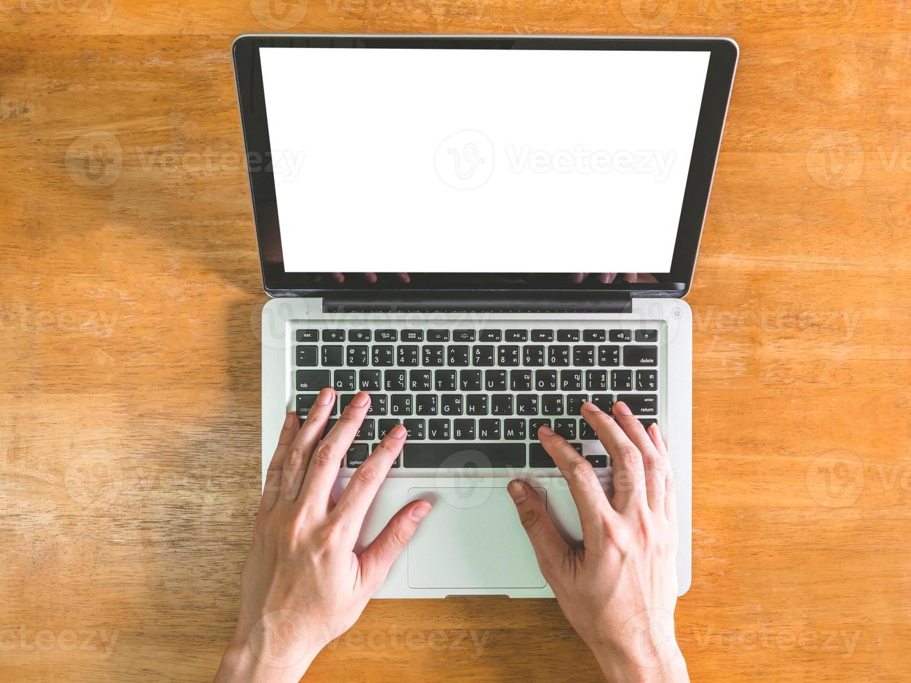 Top view of Male hands using Laptop with blank screen on wooden table photo