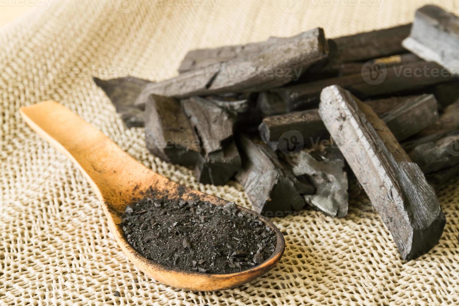 Charcoal and charcoal powder on wooden spoon. Selective focus photo